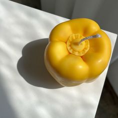 a yellow pepper sitting on top of a white table next to a knife in it's mouth