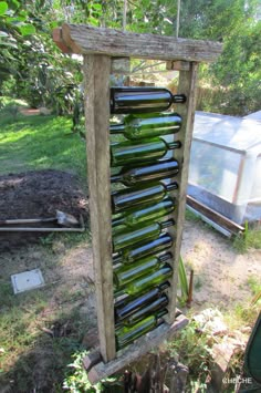 there is a wine rack made out of old bottles in the yard with a garden shed behind it