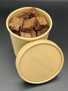 a cup filled with brownies sitting on top of a gray table next to a plate