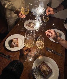 people are toasting with sparklers at a table filled with desserts and wine glasses