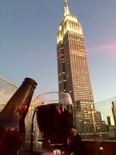 two glasses of wine are sitting on a table with the empire building in the background