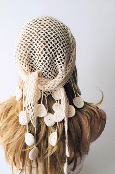 the back of a woman's head wearing a white hat with crochet circles and tassels