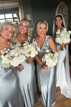 the bridesmaids are all dressed in silver gowns and holding their bouquets