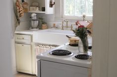 a white stove top oven sitting inside of a kitchen next to a sink and window