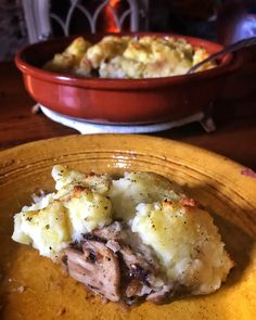 a yellow plate topped with mashed potatoes next to a red bowl filled with meat