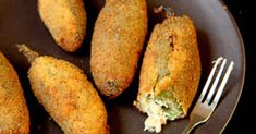 some fried food on a black plate with a fork and knife next to it,