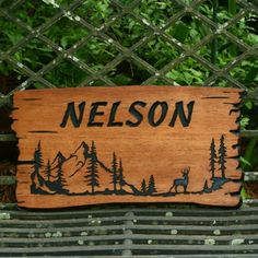 a wooden sign that says nelson with trees and mountains in the background on a bench