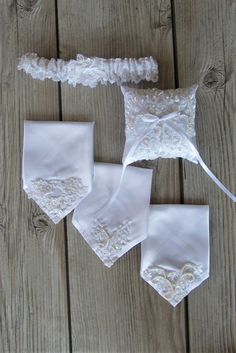 three pieces of wedding garters on a wooden floor with white lace and bows