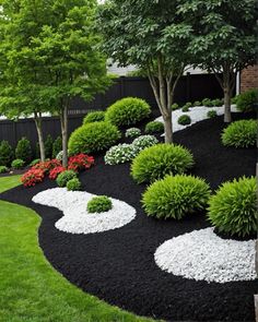 a garden with black and white landscaping in the grass, trees and bushes around it