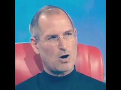 a man with glasses is sitting in a red chair and has his mouth wide open