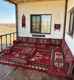 a red and white couch sitting on top of a wooden floor next to a window