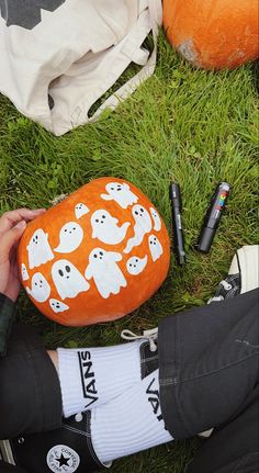 someone is sitting in the grass with their feet up on an orange pillow that has ghost faces on it