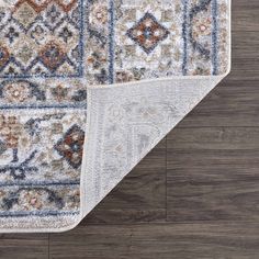 an area rug on the floor with wood floors in the background and a blue, brown, beige, and white color scheme