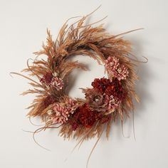 a dried wreath with red and pink flowers on white background, ready to be used as an ornament