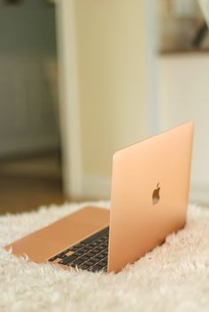 an apple laptop sitting on top of a white rug