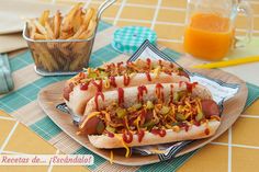 two hotdogs with condiments on a plate next to french fries and orange juice