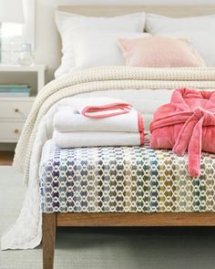 towels folded on top of a bed in a room with white walls and carpeting