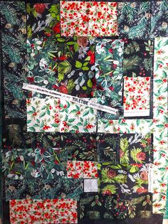 a piece of fabric that has been made into a quilt with red and green flowers on it