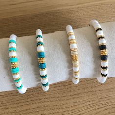 four bracelets are lined up on top of each other in different colors and sizes