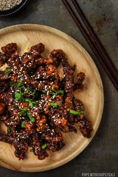 a wooden plate topped with meat covered in sesame seeds