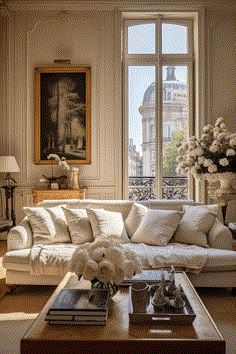 a living room filled with lots of white furniture and flowers on top of a coffee table