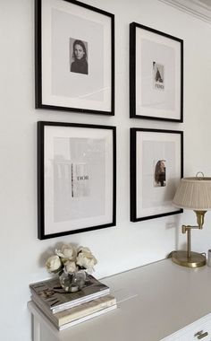 three black and white framed pictures hang on the wall above a desk with a lamp