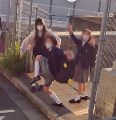 two children are walking down the sidewalk with backpacks on their back and one child is holding his hand up