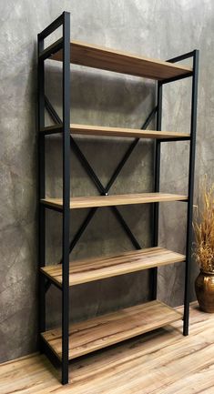 a black and wood book shelf next to a potted plant on a wooden floor