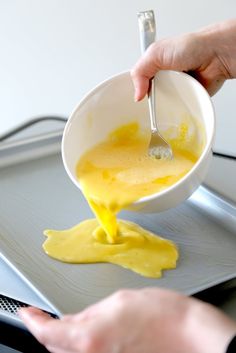 someone is pouring yellow liquid into a bowl