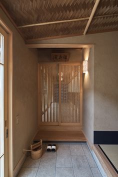 an empty room with wooden slats on the ceiling and two pairs of shoes in front of it