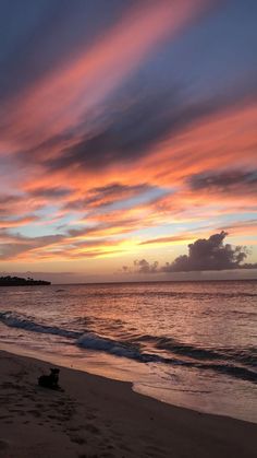 the sun is setting over the ocean with clouds in the sky and on the beach