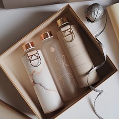 two white bottles in a box next to a silver ball and some other items on a table