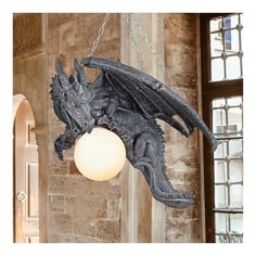 a dragon lamp hanging from a chain in a room with stone walls and arched windows