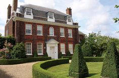 a large red brick house surrounded by hedges