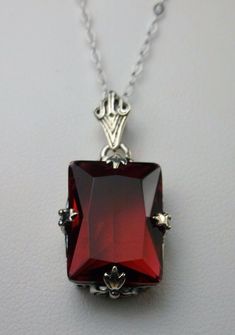 Simulated Red Ruby Pendant Description GL Design#15 Custom-Made This is a brand new stunning Art Deco style sterling silver filigree 10ct Simulated/man-made red ruby pendant necklace. The beautiful rectangle-cut ruby gem is 16mm in length 12mm in width. The 1.5mm necklace chain is 18 inches in length. The entire pendant is 1 1/8th inches long by 9/16th inches wide. Notice the beautiful craftsmanship of the silver Deco filigree bail. This is a lovely new, well made/sturdy, pendant and necklace it Classic Red Jewelry As A Gift, Classic Red Ruby Jewelry, Classic Red Hallmarked Necklace, Formal Red Faceted Necklace, Fine Jewelry Ruby Red, Fine Jewelry Red Ruby, Red Ruby Fine Jewelry, Formal Ruby Jewelry With Faceted Details, Red Sterling Silver Fine Jewelry