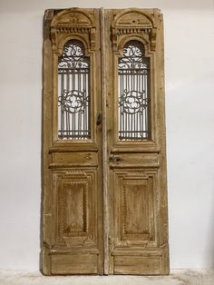 an old pair of wooden doors with wrought iron grills on the top and bottom