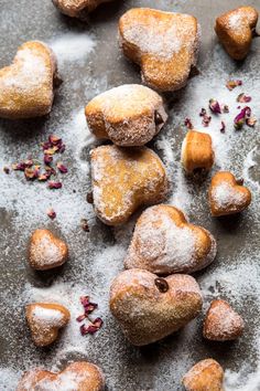 several heart shaped pastries on a table with powdered sugar and cranberries