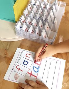 a child's hand is writing on paper next to a stack of letter cards