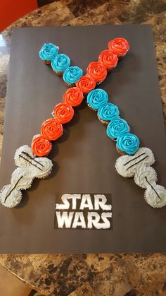 a cake shaped like the letter x with roses on it and star wars written in white