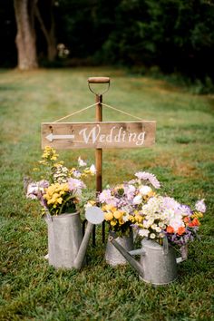 two watering cans with flowers in them and a sign that says wedding