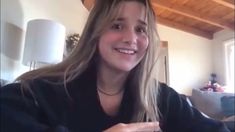 a young woman is smiling and looking at the camera while sitting in her living room