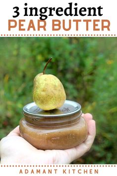 a hand holding a jar filled with peanut butter and an apple sitting on top of it