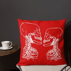 a red pillow sitting on top of a chair next to a cup