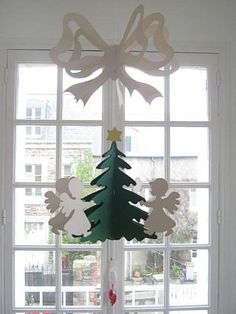 a christmas tree hanging from the side of a window in front of a white wall