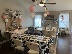 a room filled with tables and chairs covered in black and white cow print tablecloths