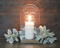 a candle is lit in front of a glass plaque with the words loving memory on it