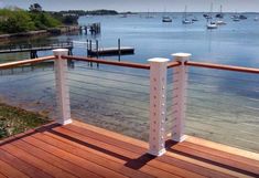 a wooden deck with white railings and boats in the water