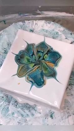 there is a white plate with blue and green flowers on the inside, sitting on some plastic