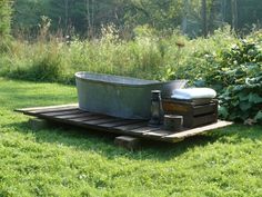 an old bath tub sitting on top of a wooden pallet in the middle of a field