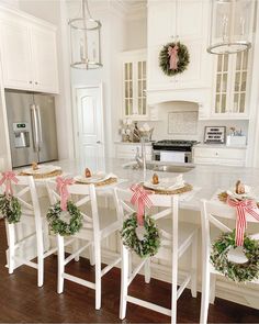 the kitchen is decorated for christmas with wreaths on the island and garland around the chairs